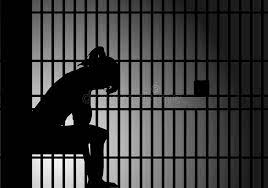 A lady sitting in despair inside jail custody